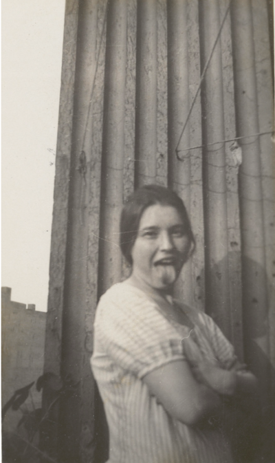 Schwarz-weiss Foto von Netty Reiling als junge Frau. Sie streckt die Zunge raus und lächelt.