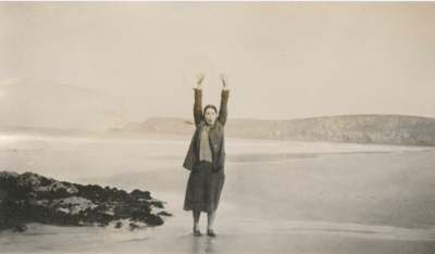  Schwarz-weiss Foto von Netty Reiling am Strand. Sie streckt die Arme freudig in die Luft.