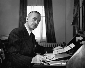 Schwarz-weiss-Fotografie von Fred Stein. Abgebildet wird ein Mann an einem Schreibtisch mit einem Blatt Papir und einer Brille in der Hand.